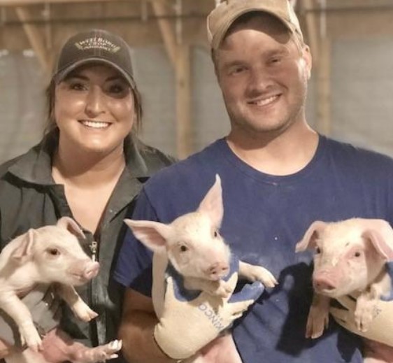A man and a woman both holding piglets