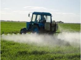 Photo of a field being sprayed by a boom sprayer on a tractor.