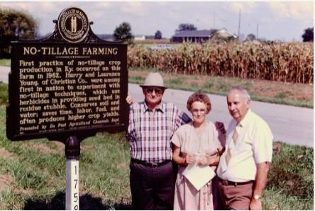 Harry Young, Marie Young and Shirley Phillips, UK agronomist, pose next to the No-Tillage Historical Marker on the Youngs' farm