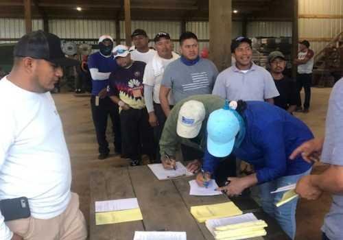 Agricultural workers signing in for a farm food safety training prior to harvest