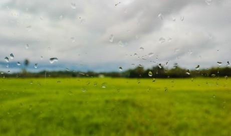 Rain drops on camera lens looking onto field.